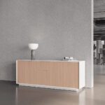 Minimalist white and wood office sideboard with a drawer cabinet, stylish lamp, and textured gray wall.