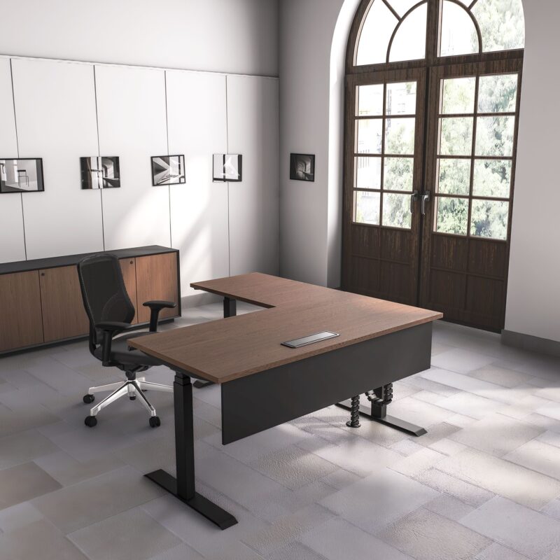 Executive office with a dark wood L-shaped standing desk, black mesh chair, and large arched window.