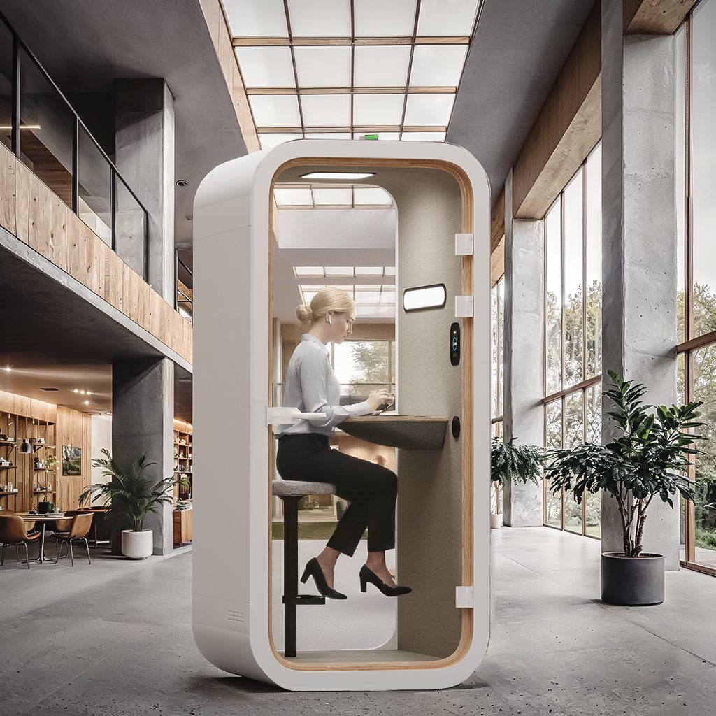 Image of a woman working inside a soundproof office pod in an office setting