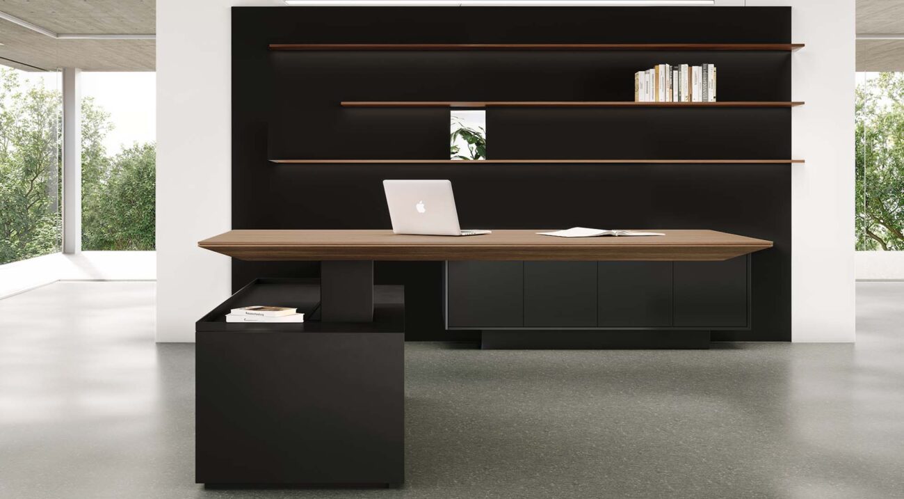 Contemporary height-adjustable standing desk setup with a large wooden surface, minimalist black cabinets, and a laptop, overlooking bright windows.
