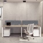 Bright dual workstation with wood-look desks, mobile storage, and a white mesh office chairs Dubai against a concrete wall.