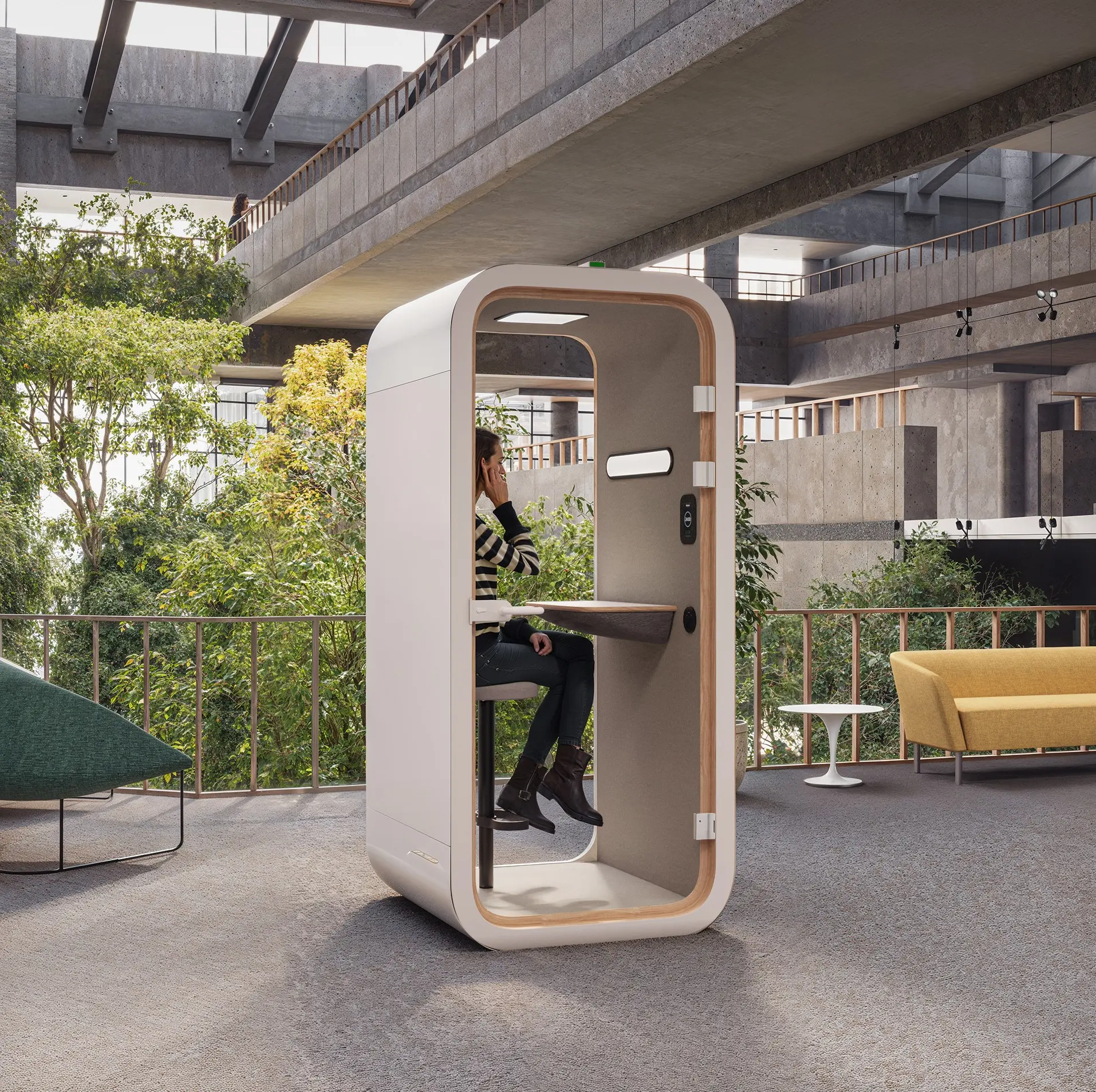 Individual soundproof white meeting pods phone booth with a seated person making a call in an open office area.