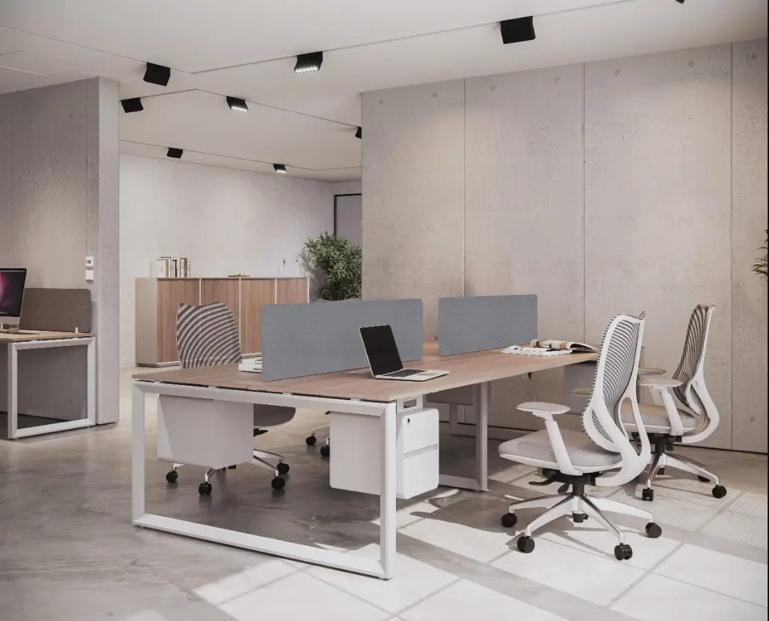 Minimalist shared office workstation with light wood desks, grey dividers, and ergonomic mesh office chairs.