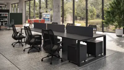 A black multi-person office workstation cluster by Urban 411, featuring integrated privacy dividers, under-desk storage pedestals, and ergonomic mesh task chairs in a modern open-plan office setting with a nature view.